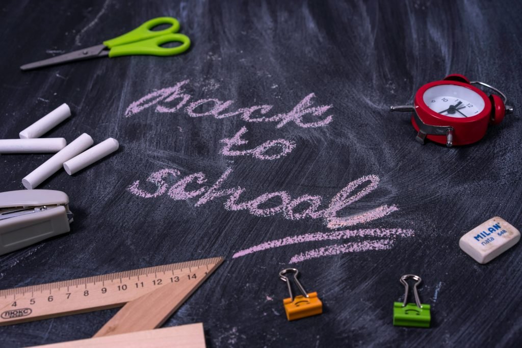 Back to school chalkboard with school supplies and 'back to school' written in pink chalk.